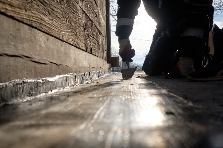a workers gluing bitumen on a porch