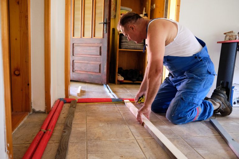 a worker measuring distance between planks on a floor