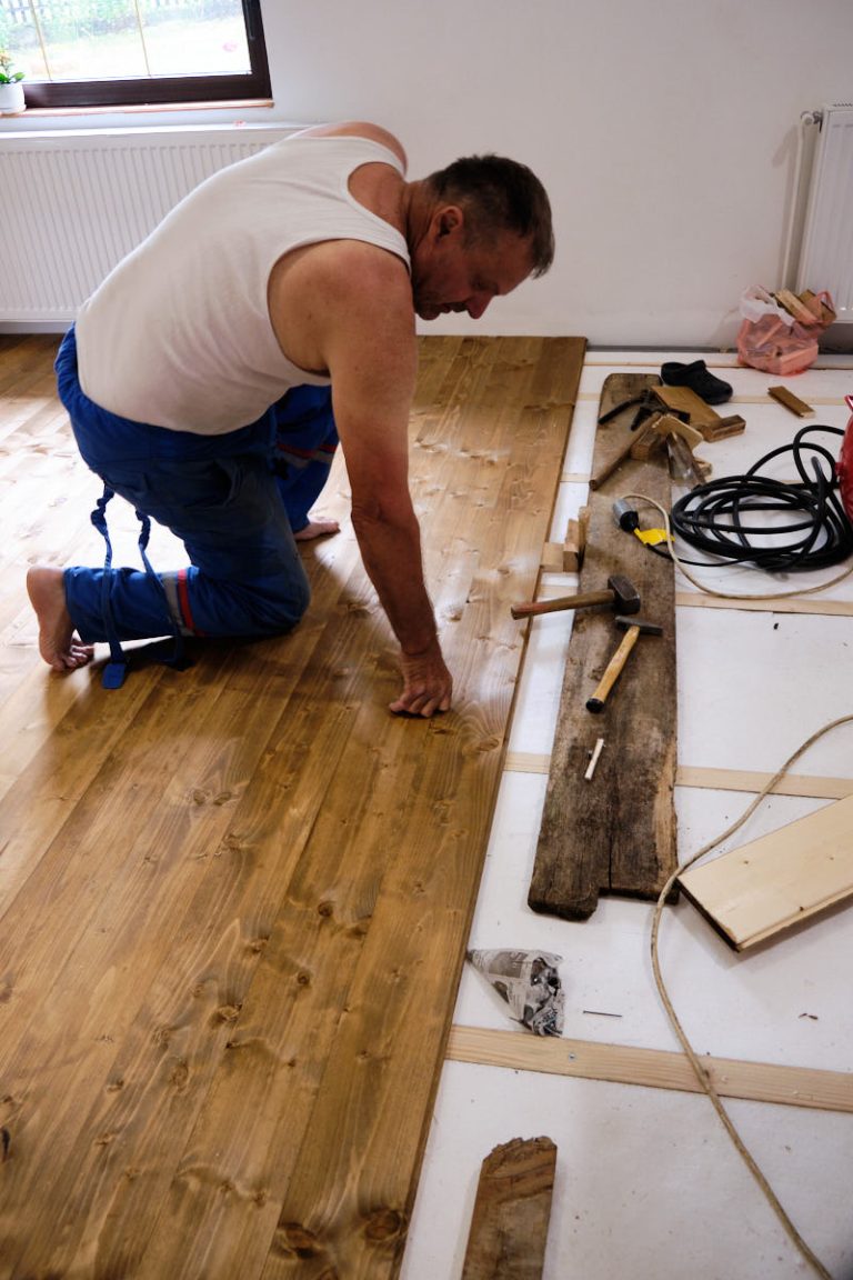 a worker installing wooden floor boards in a room