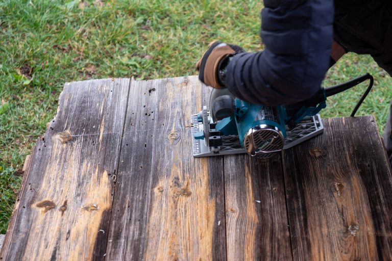a worker cutting wood with an electric hand saw