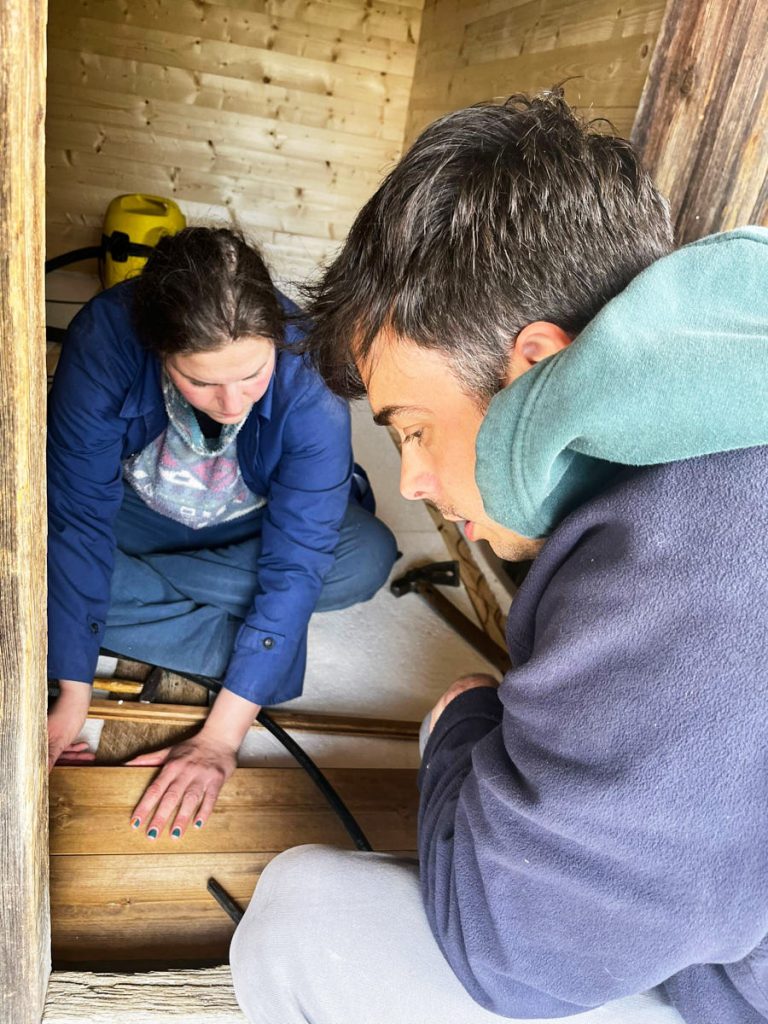 a man and a woman working on a wooden cottage floor