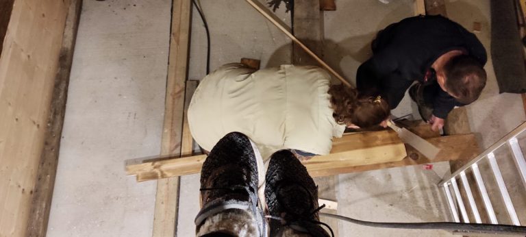 a man and a woman sawing a wooden plank