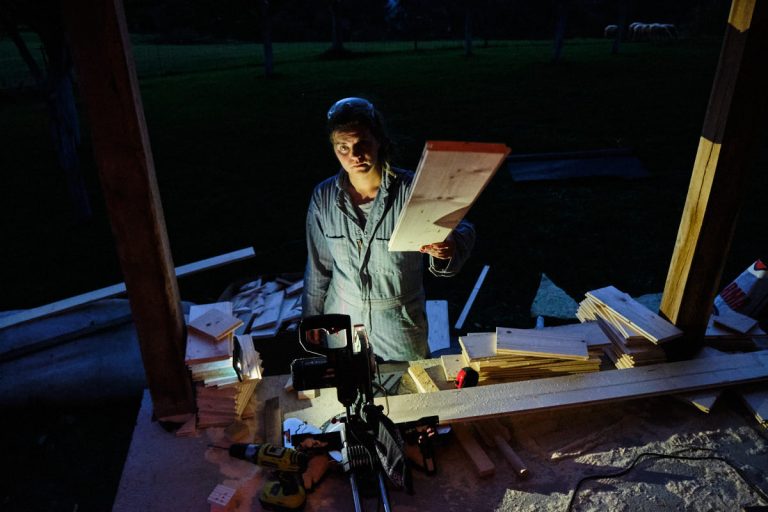 a woman with a wooden baord and a miter saw