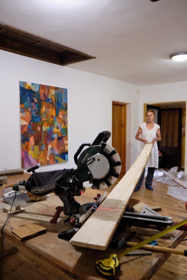 a woman holding a plank on a mitter saw
