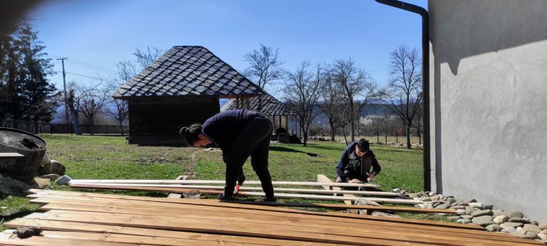 a man and a woman painting wooden planks