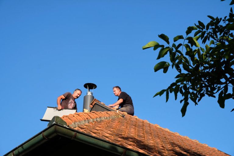 workers on a roof installing a chimney