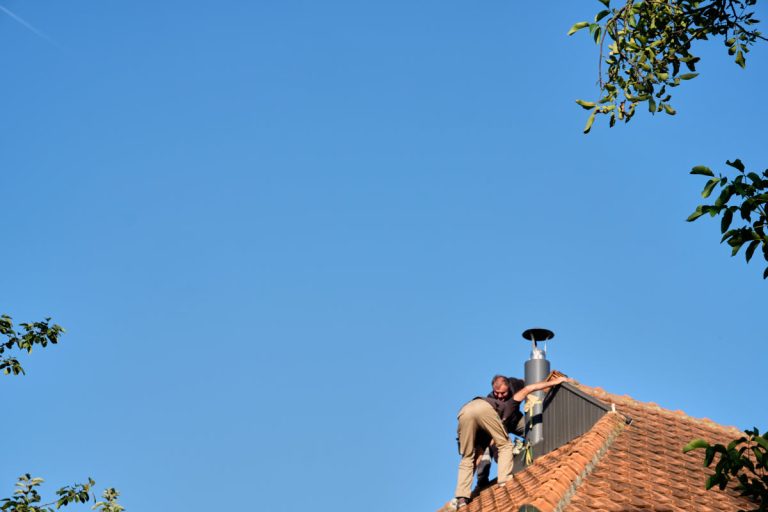workers on a roof installing a chimney